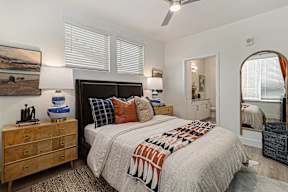 A bedroom with a large bed and a wooden dresser.