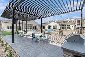 A patio with a table and chairs under a black and white striped awning.