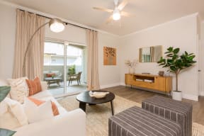 a living room with a ceiling fan and a sliding glass door to a patio
