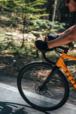 A person riding a bicycle with a black and orange frame.