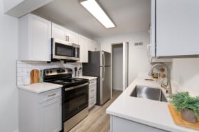 a white kitchen with stainless steel appliances and white cabinets at Terra Vista at the Park Apartments, Littleton, CO, 80123