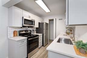 A kitchen with white cabinets and a black stove top oven. at Terra Vista at the Park Apartments, Littleton, Colorado