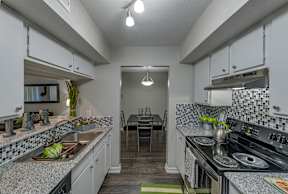 A kitchen with a dining table and chairs in the middle.