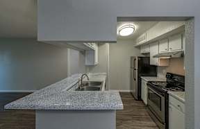 A kitchen with a granite countertop and stainless steel appliances.