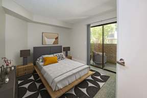 A bedroom with a bed, nightstand, and chair.