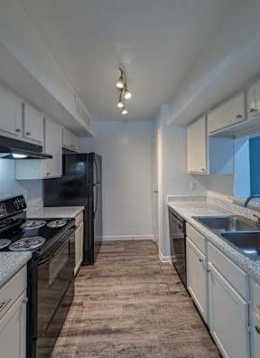 A kitchen with black appliances and white cabinets.