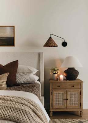 A bedroom with a bed, a nightstand with a lamp, and a painting on the wall.