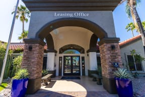 a view of the leasing office with a blue sky and palm trees in the background