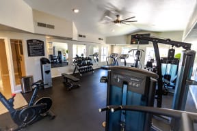 a spacious fitness room with cardio equipment and weights