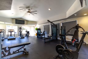 a home gym with exercise equipment and a ceiling fan