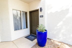 the front door of a white building with a blue planter in front of it