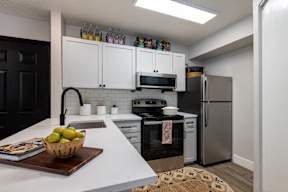 A kitchen with white countertops and a black refrigerator.
