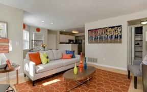 A living room with a white couch and orange pillows.