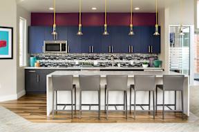 A kitchen with a bar area and grey chairs.
