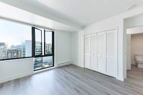 A room with a large window and a toilet in the corner.
