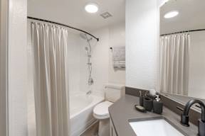 A white bathroom with a shower curtain and a toilet.