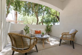 a patio with two rattan chairs and a table