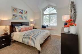 A bedroom with a bed, nightstand, and a window.