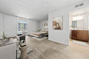 A bedroom with a bed, a chair, and a painting on the wall.