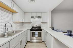 A modern kitchen with white cabinets and a stainless steel oven.