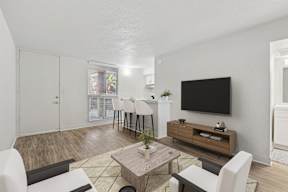 A living room with a white couch, a wooden coffee table, and a flat screen TV mounted on the wall.