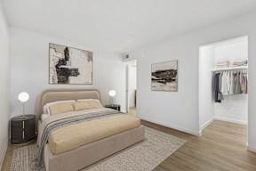 A bedroom with a bed, two lamps, and two pictures on the wall.