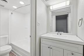 A white bathroom with a toilet, sink, and mirror.