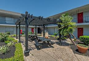 A patio area with a table and chairs under a pergola.