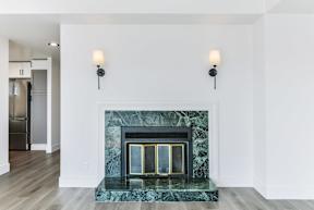 A fireplace with a green marble mantle and two wall sconces.