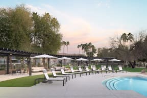 a pool with lounge chairs and umbrellas next to a pool