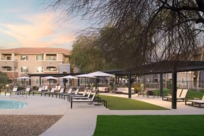 a patio with chairs and umbrellas and a pool in front of a hotel