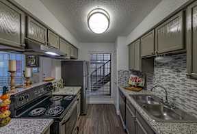 A kitchen with a black stove top oven and a black refrigerator.