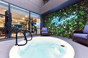 A hot tub sits in the middle of a room with a green wall behind it.