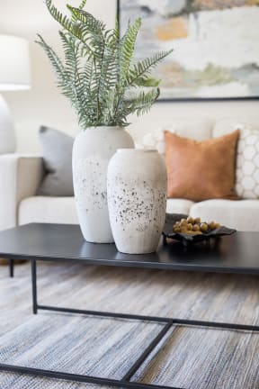 a coffee table with two white vases and a plant on it