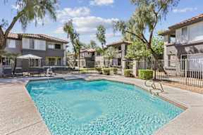 A swimming pool in a residential area surrounded by houses and trees.
