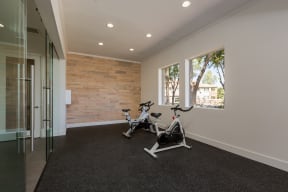 a home gym with a wood accent wall and exercise bikes