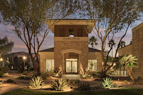 A building with a sign that says "LEASING OFFICE" is surrounded by plants and trees.
