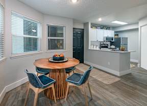 A kitchen with a table and chairs in the foreground and a refrigerator in the background.