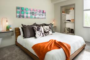 A bedroom with a bed, a painting, and a shelf.