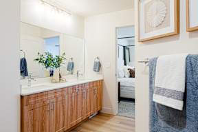 A bathroom with a white counter top and wooden cabinets.