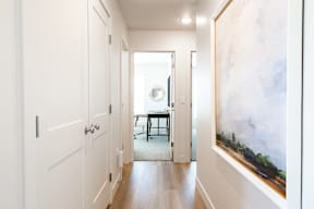 A hallway with a painting on the wall and a table in the background.