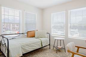 A bedroom with a bed, chair, and window.