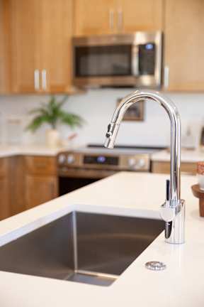 A modern kitchen with a stainless steel sink and a silver faucet.