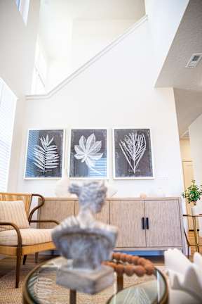 A living room with a chair, a table, and three framed pictures on the wall.