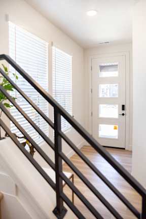 A staircase with a metal railing and wooden steps leading to a white door.
