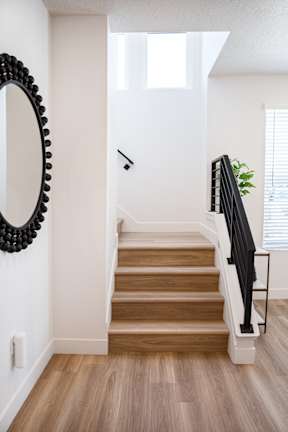 A staircase with a wooden handrail and a mirror on the wall.