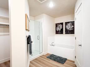 A bathroom with a glass shower door and a white bathtub.