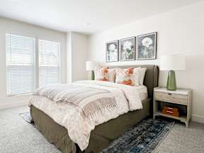 A bedroom with a large bed and a nightstand with a lamp.