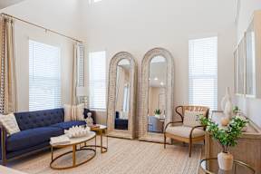 A living room with a blue couch, a coffee table, a chair, and a large mirror.