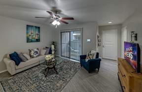 A living room with a white couch, a blue chair, a coffee table, and a flat screen TV.